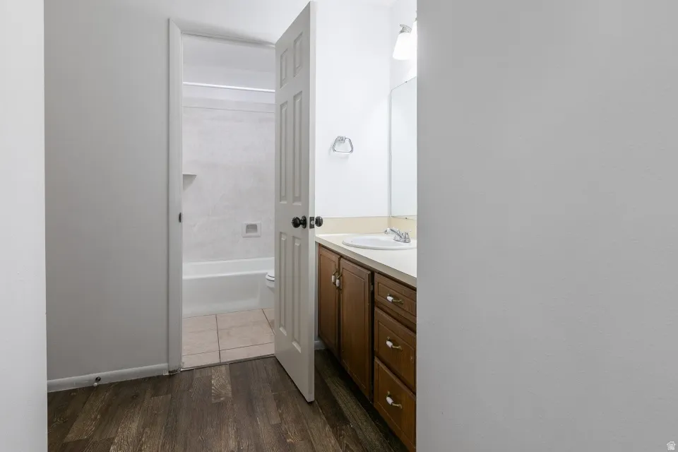 Bathroom featuring a wood-finish vanity with an integrated sink, cream-toned countertop, and a built-in mirror