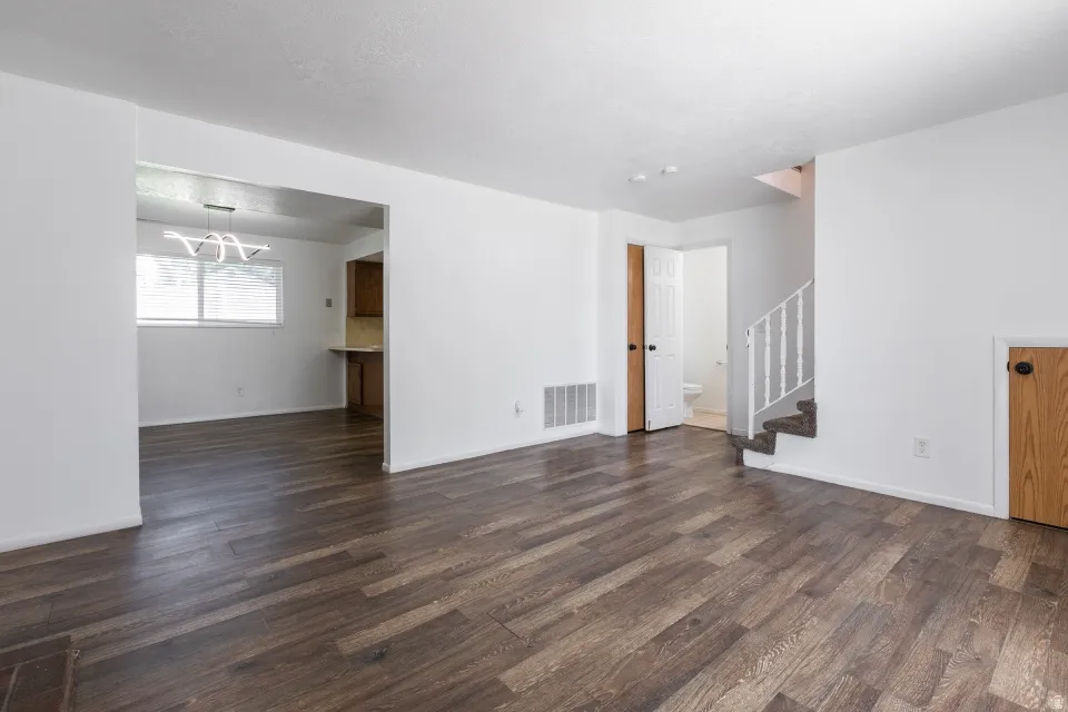 Wood-finish flooring throughout, white painted walls, and a modern linear chandelier
