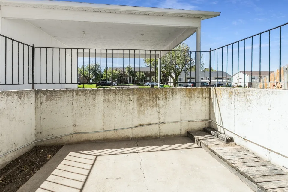 Covered patio space featuring a concrete floor, concrete retaining walls, and a wood plank ramp