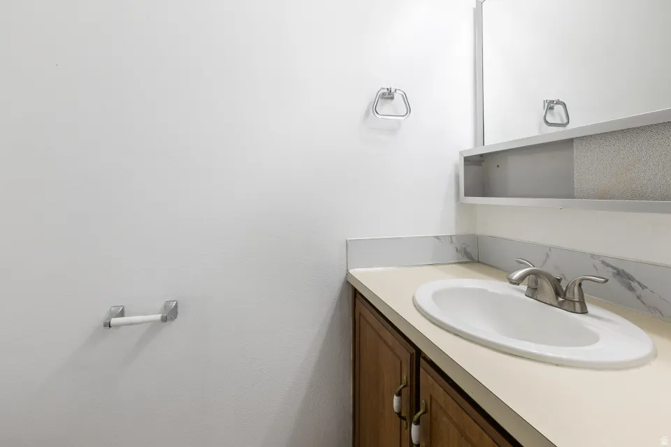 Vanity with a built-in sink, brushed nickel faucet, wood-finish cabinetry, and a mirrored medicine cabinet