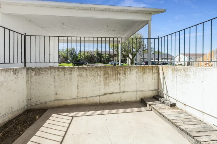 Covered patio space featuring a concrete floor, concrete retaining walls, and a wood plank ramp