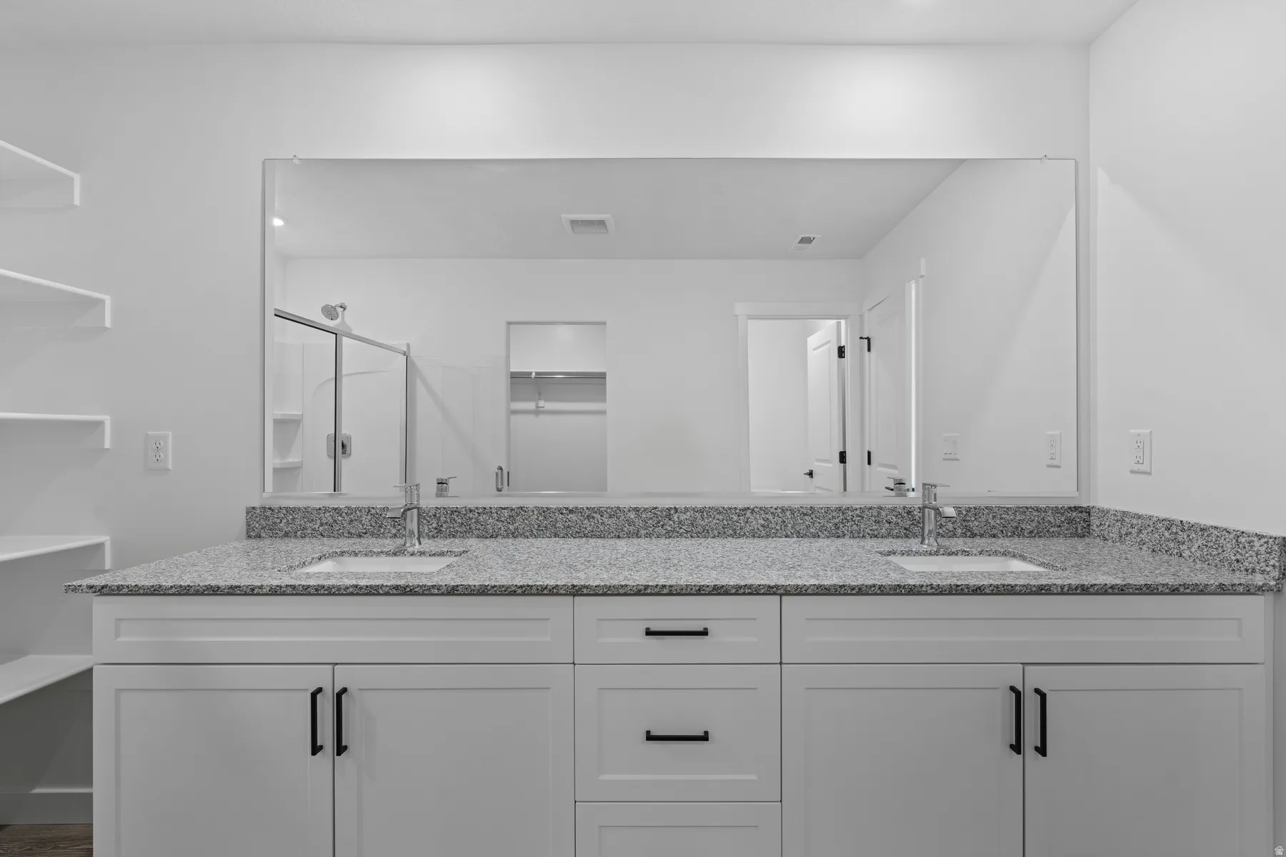 Double vanity with granite countertop, undermount sinks, and white shaker-style cabinetry