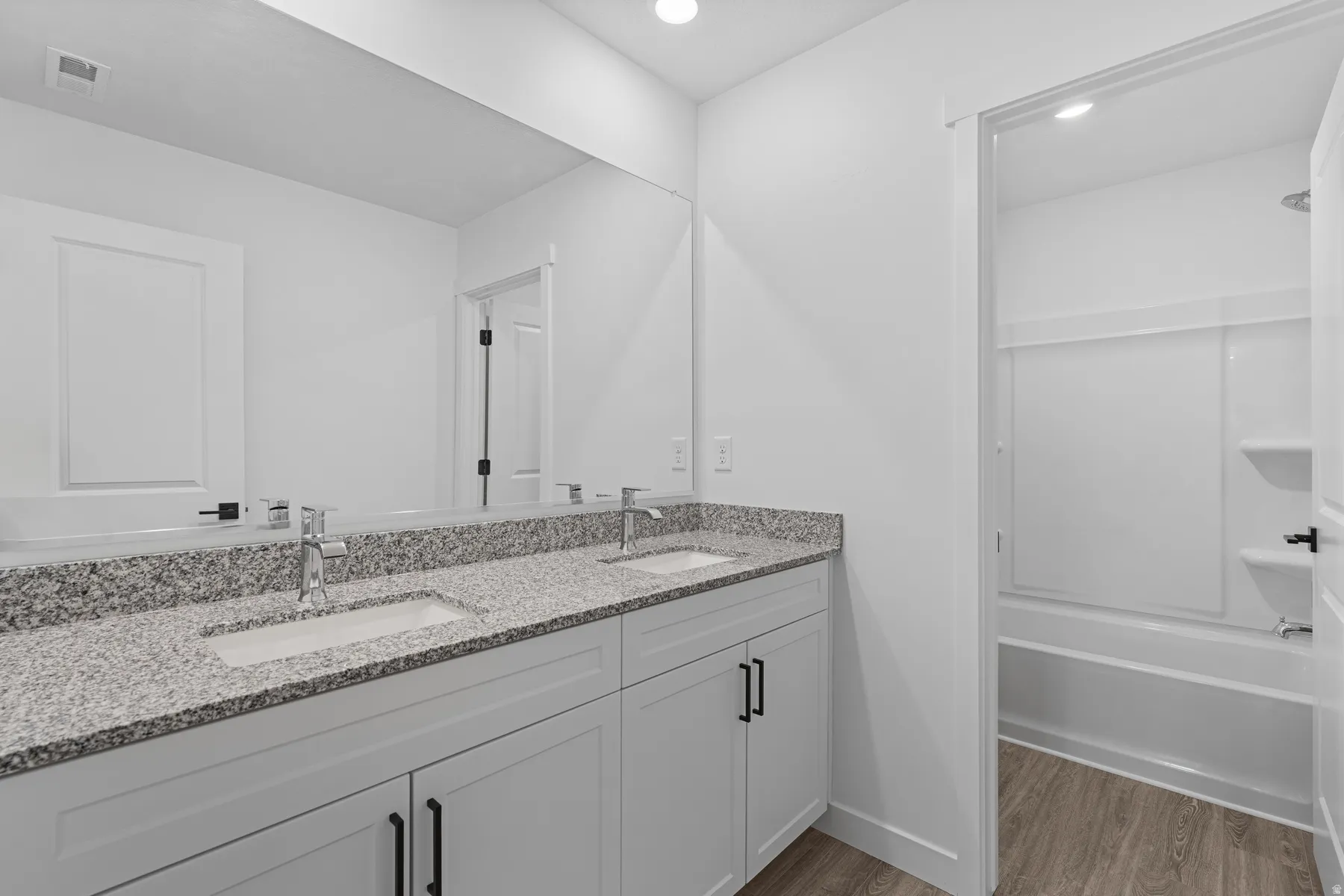 Dual vanity with a stone-finish countertop, under-mount sinks, and chrome fixtures