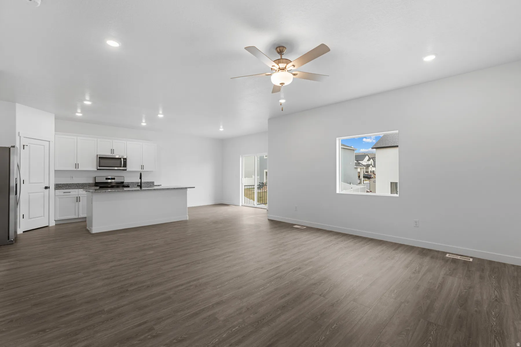 Open-concept living area featuring wood-finish flooring, recessed lighting, and a ceiling fan