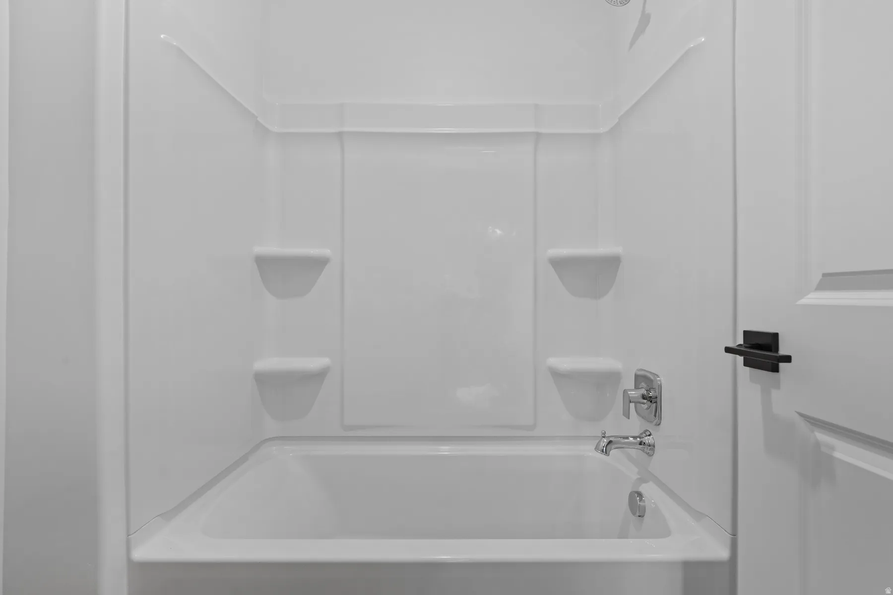 White tub and shower combination with built-in shelving