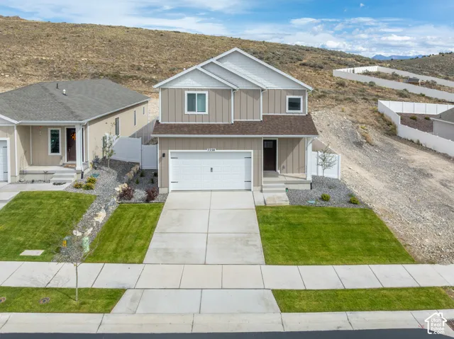 Two-story residence featuring a two-car garage, front entry porch, and partial siding exterior