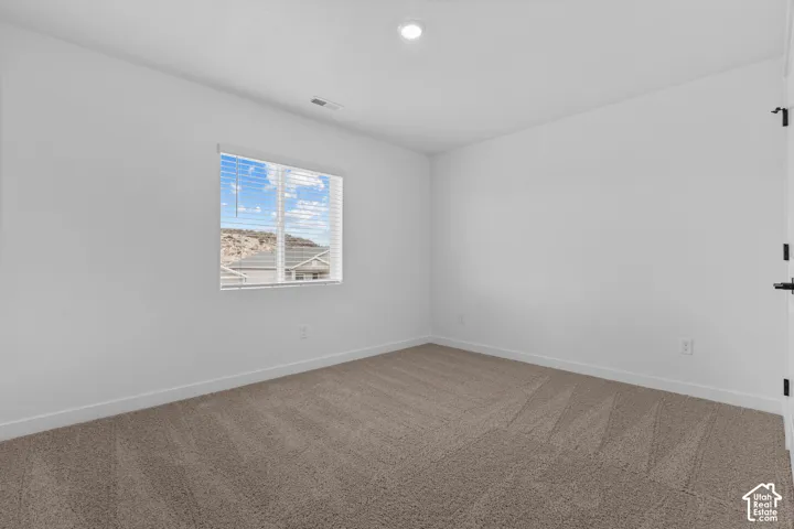 Room featuring neutral carpeting, white walls, a single window with blinds, and a ceiling-mounted light fixture