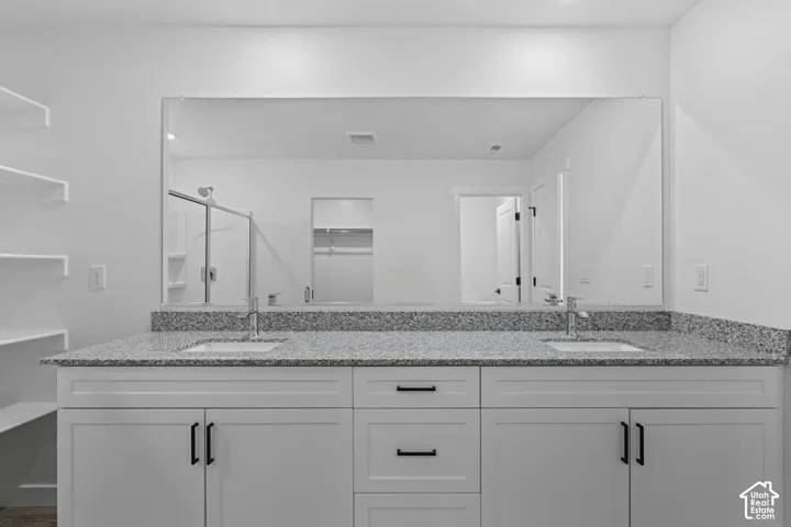 Double vanity with granite countertop, undermount sinks, and white shaker-style cabinetry