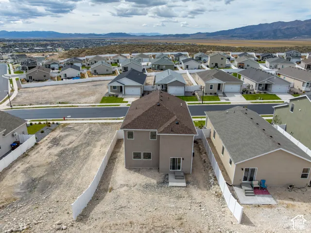 Two-story property with a brown shingle roof, rear patio, and white vinyl perimeter fencing