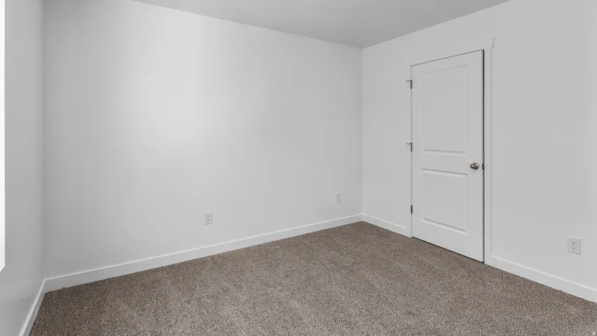 Neutral wall tones with a two-panel interior door, featuring textured carpeting and white trim