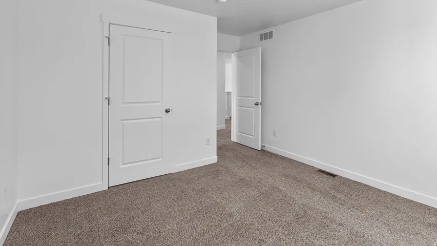 Wall-to-wall carpeting in a neutral tone, white painted walls, and white trim accents