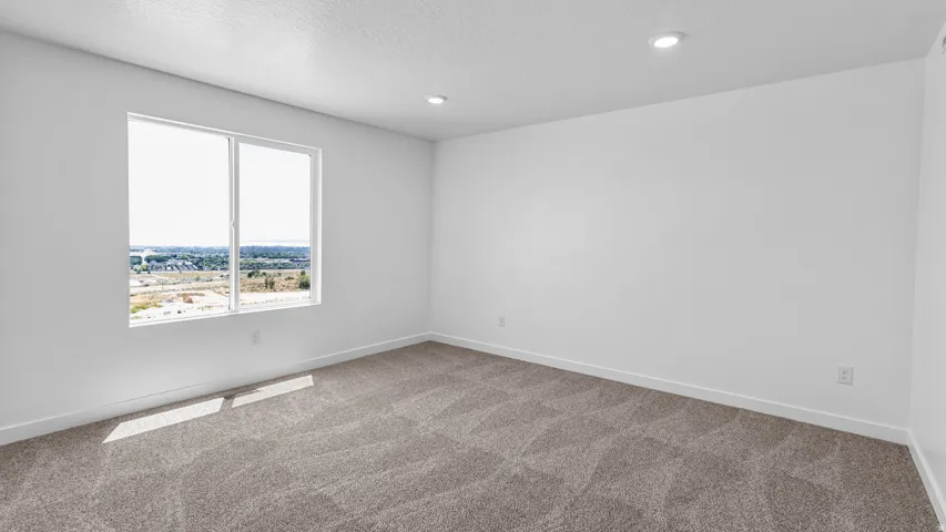 Expansive room with neutral carpeting, recessed ceiling lighting, and a large window