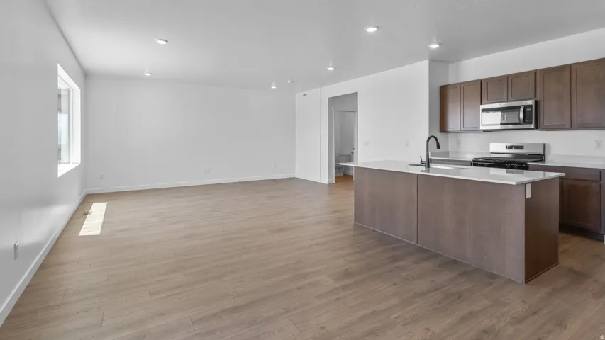 Open-concept living space with wood-finish flooring, recessed lighting, and a large window