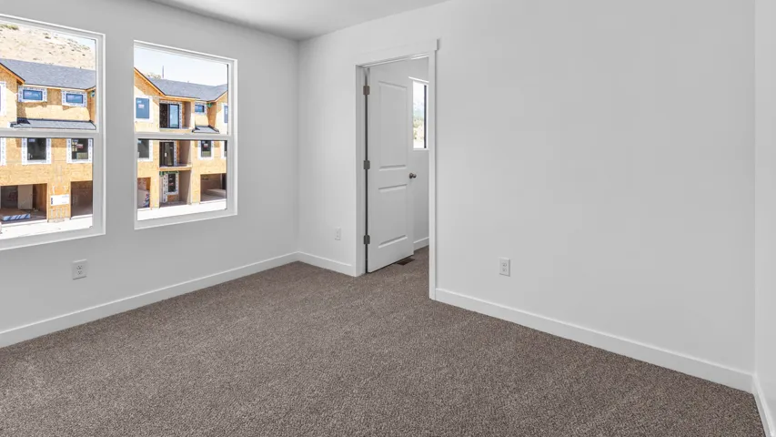 Carpeted flooring with white trim, white walls, and two large windows
