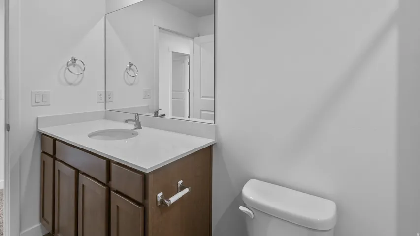 White countertop vanity with an undermount sink, chrome faucet, and wood-finish cabinetry