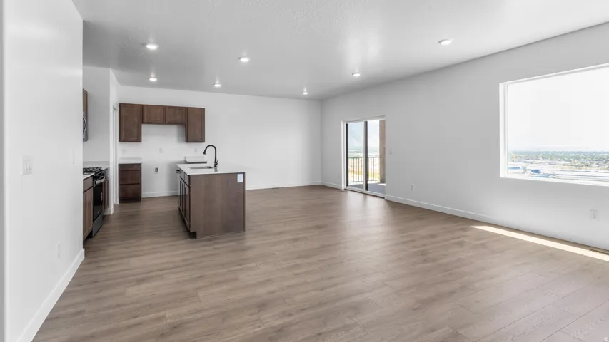 Open-concept living space with wood-finish flooring, recessed lighting, and white walls