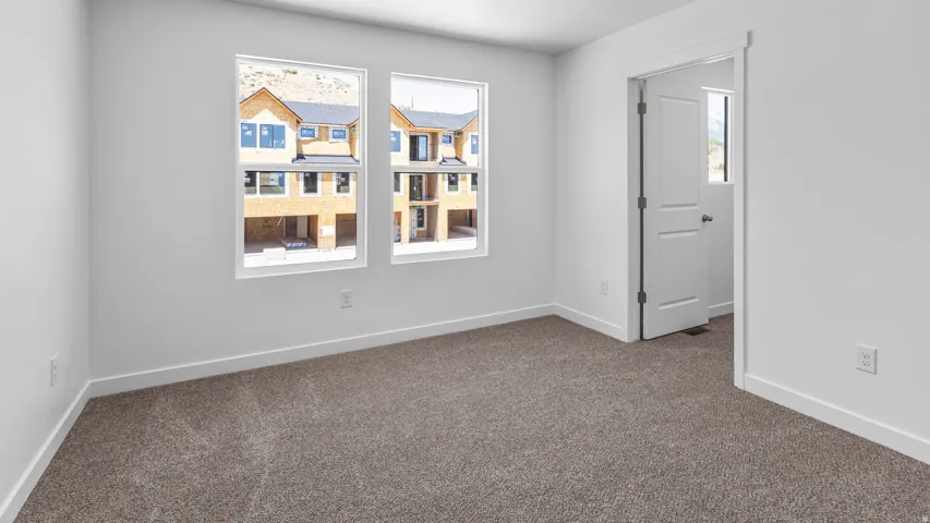 Neutral tone paint scheme, carpet flooring, dual windows, and a paneled interior door