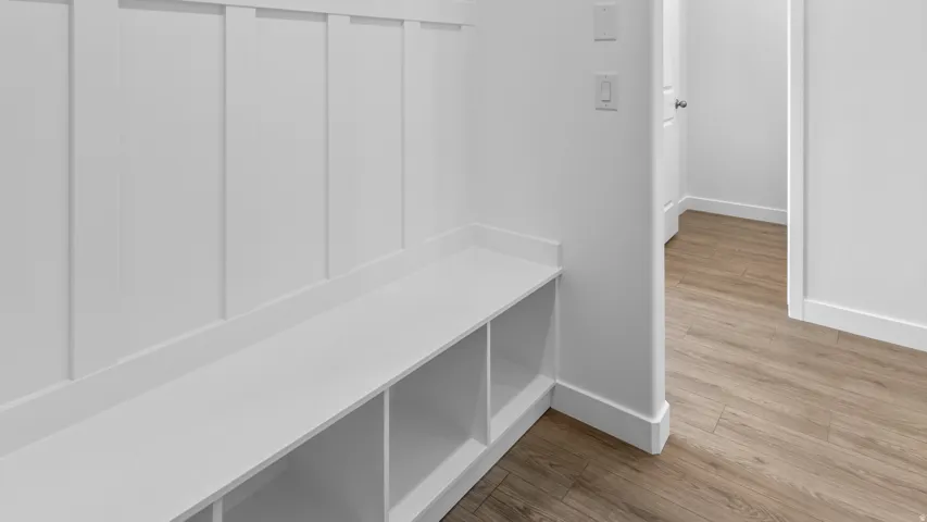 Built-in storage bench with cubbies, wainscoting, and wood-finish flooring