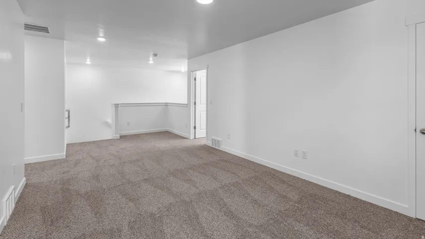 Expansive carpeted area with recessed lighting, white painted walls, and white trim