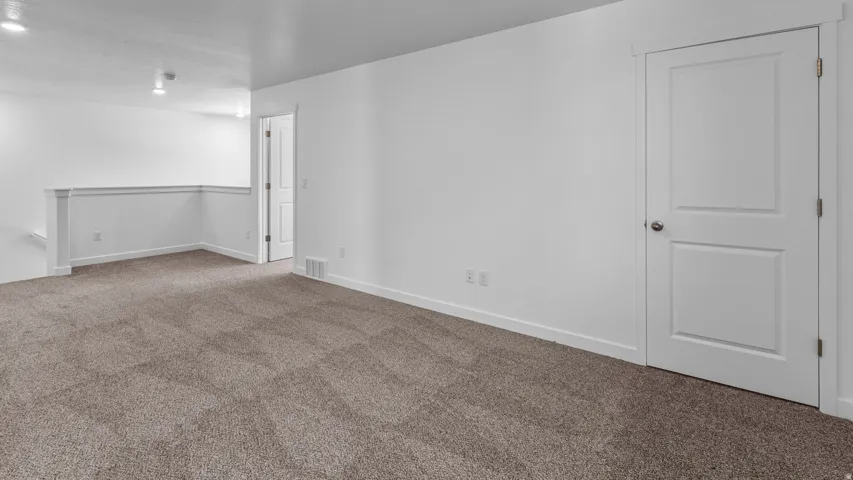 Neutral color palette, plush carpeting, white trim, recessed lighting, and a paneled interior door
