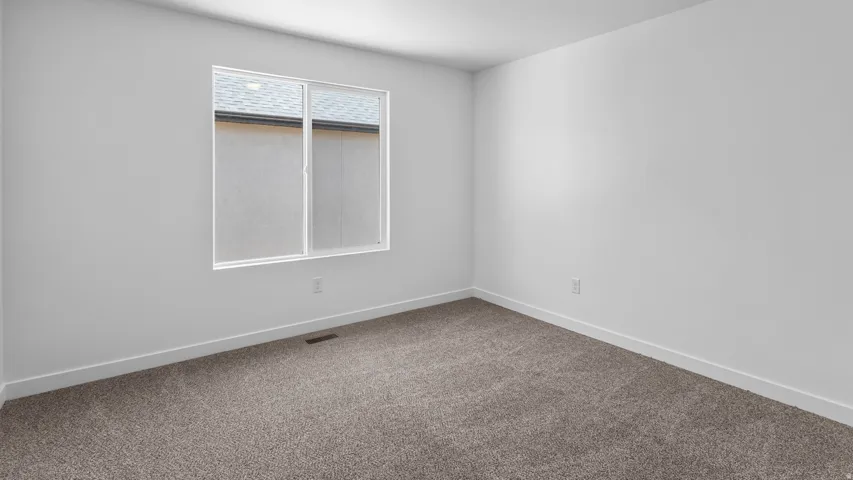 Neutral tone wall paint, carpeted flooring, and a single pane window