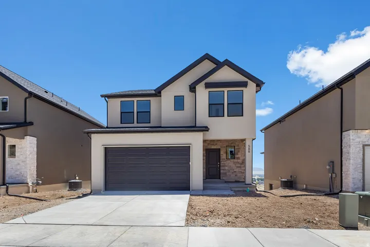 Contemporary two-story exterior with stucco siding and stone accents, featuring a two-car garage, dark trim windows, and a concrete driveway