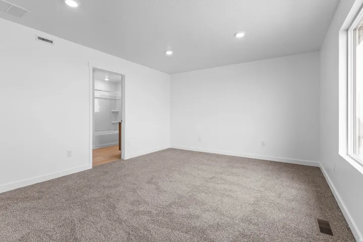 Carpeted room with recessed lighting, an interior doorway, and a window