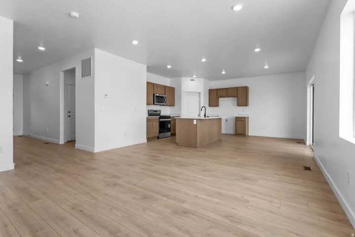 Open-concept living space featuring wood-finish flooring, recessed lighting, and a kitchen with stainless steel appliances