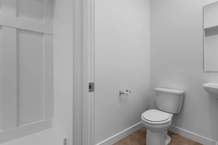 White walls with board and batten detailing, wood-finish flooring, and a white pedestal sink