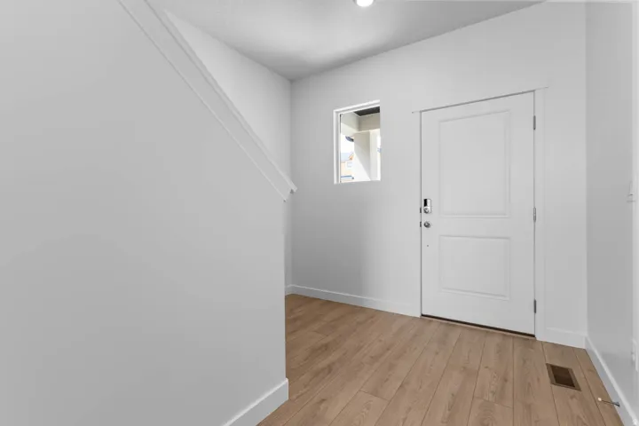 Wood-finish flooring, white paneled door, and a recessed window