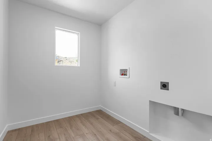 Wood-finish flooring, white walls, and a window providing natural illumination