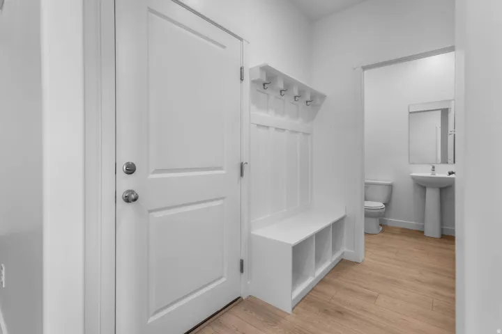 Entryway featuring wood-finish flooring and a built-in bench with storage cubbies and coat hooks