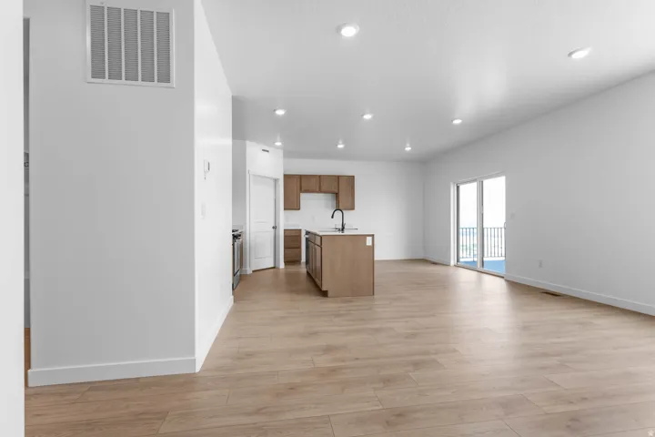 Open-concept living area featuring wood-finish flooring, recessed lighting, and a kitchen island with a built-in sink
