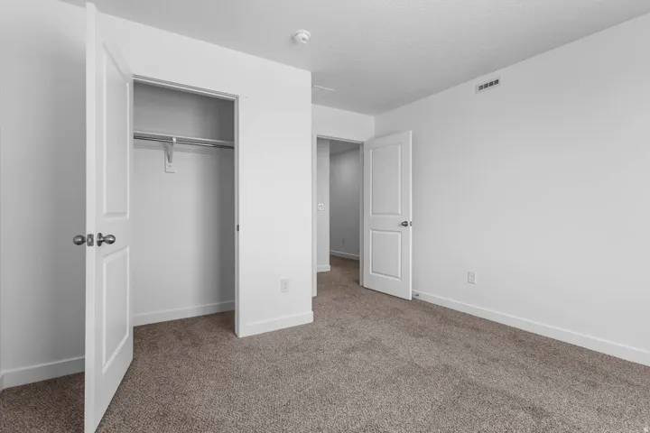 Carpeted room with white walls, a built-in closet, and interior doors with brushed nickel hardware
