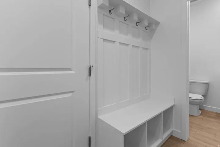 Built-in storage bench with cubbies, shaker-style paneling, and coat hooks