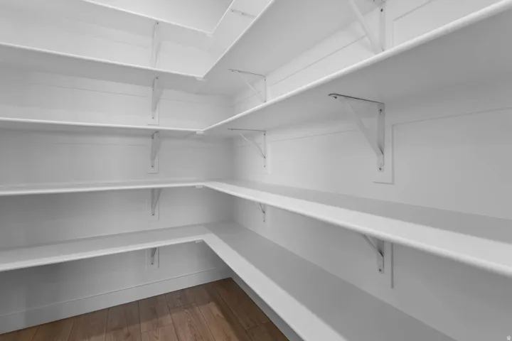 Expansive pantry with multiple tiers of wrap-around shelving and wood-finish flooring