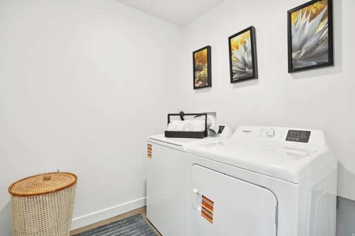 Laundry area with white walls and wood-finish flooring