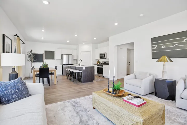 Open-concept living area with wood-finish flooring, recessed lighting, and a kitchen island with seating