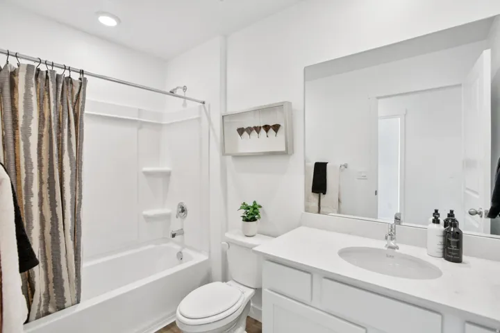 White vanity with a single basin sink and a stone-finish countertop