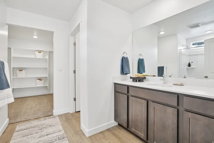 Dual vanity with white countertop, undermount sinks, and wood-finish cabinetry