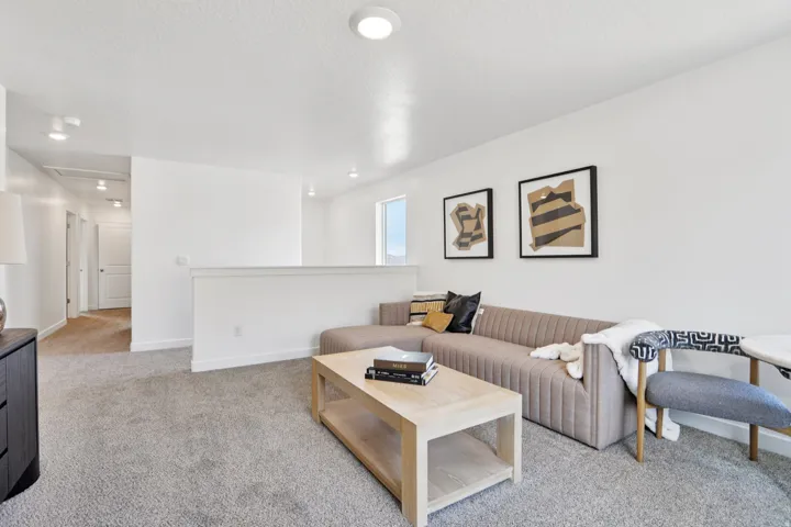 Recessed lighting, light gray carpet, half wall partition, white walls, and a window providing natural illumination