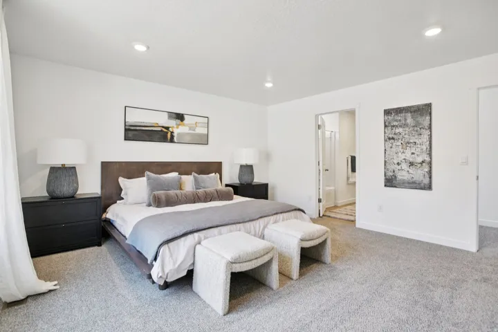 Spacious room with recessed lighting, light gray carpeting, and a doorway revealing a bathroom with a standing shower