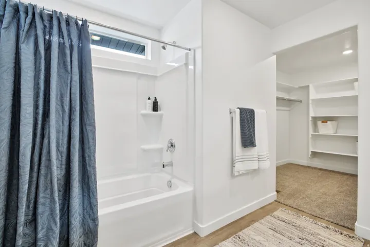 Bathtub with integrated shelving, chrome fixtures, and a transom window