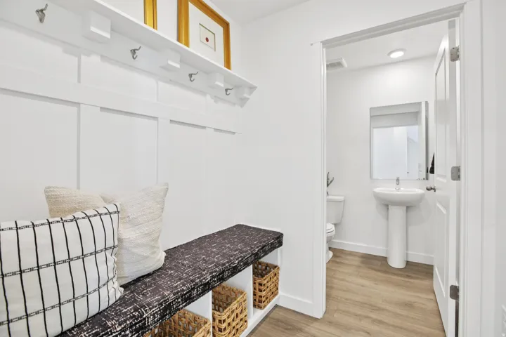 Built-in bench with cubby storage, white board-and-batten wall treatment, and a wall-mounted coat rack