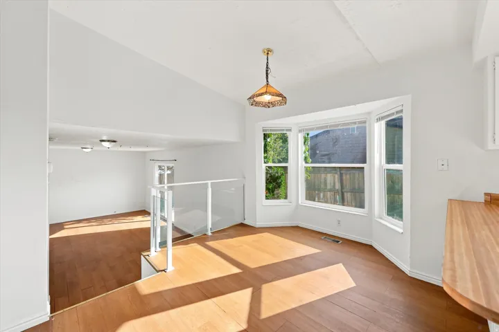 Hardwood-style flooring throughout, white walls, and a bay window