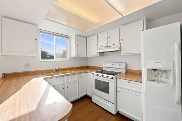 White cabinetry with polished hardware, wood-finish countertops, and matching appliances