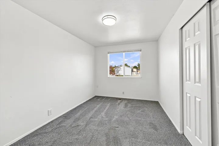 Recessed window with white trim, gray carpet, white walls, and a white bi-fold closet door