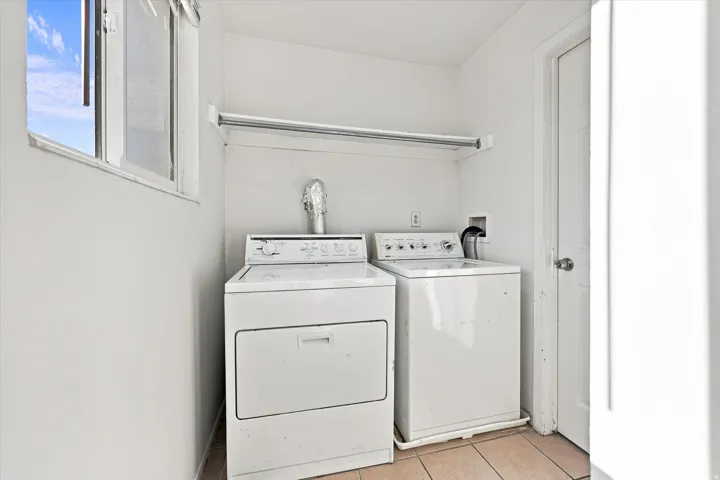 Dedicated utility area featuring a window, built-in shelf, and tile flooring