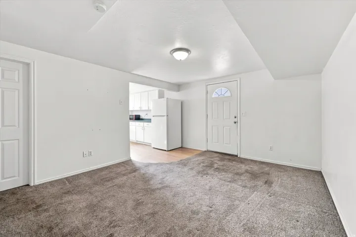 Carpeted living area with white walls and a white paneled door