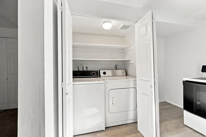 Dedicated laundry closet featuring a washer and dryer, built-in shelving, and overhead lighting